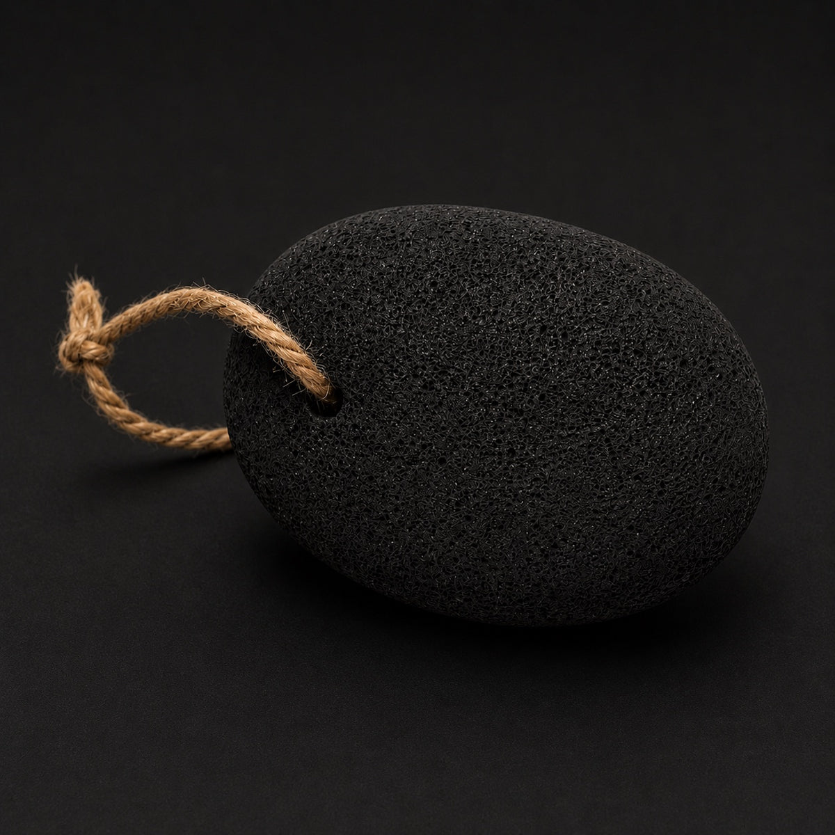 The Jhama volcanic foot stone with a rope loop on a dark surface