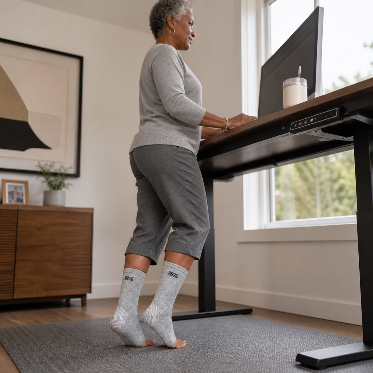Person working at a standing desk in gray toeless ANVIL foot sleeves.