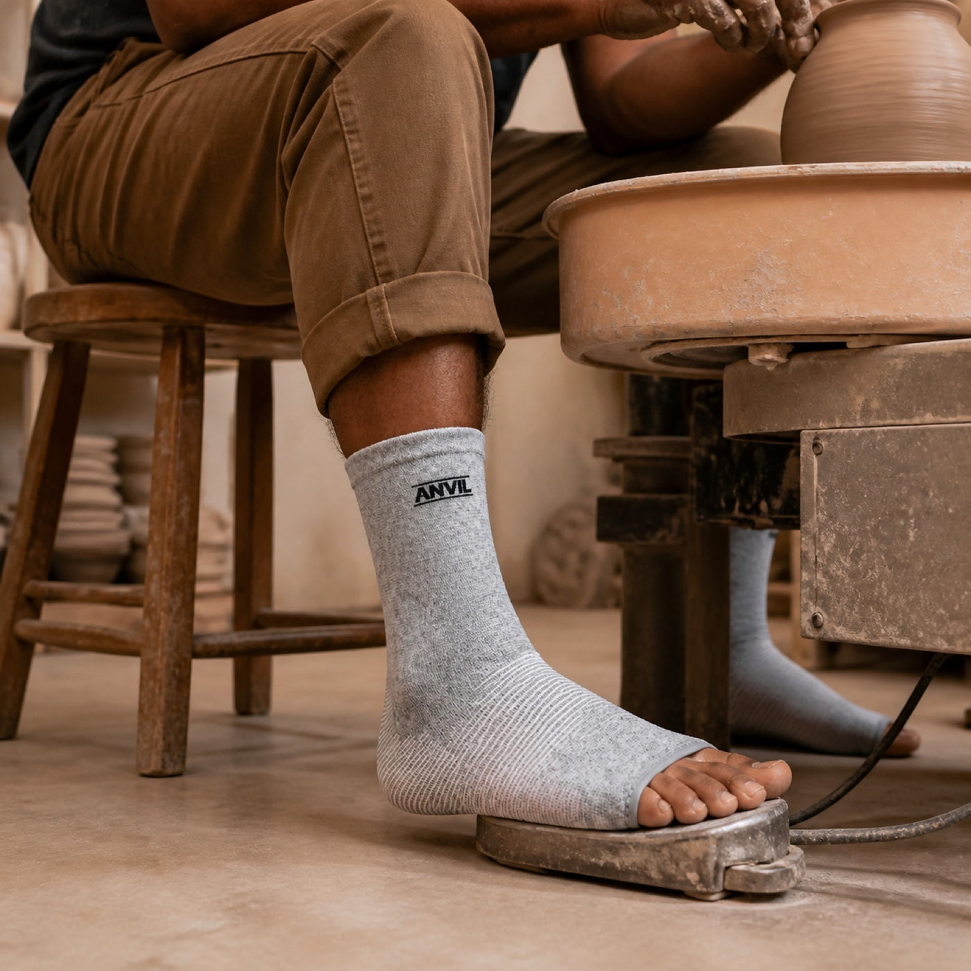 Person working in a pottery studio in gray toeless ANVIL foot sleeves.