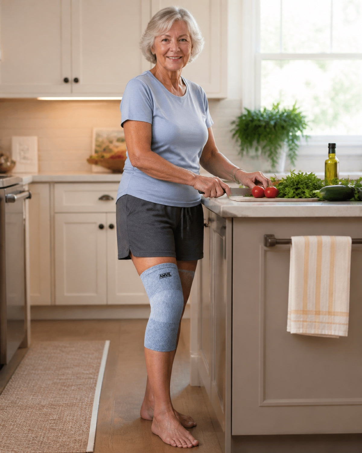 Older woman chopping vegetables at a kitchen island, with a gray ANVIL knee sleeve on her right knee.