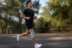 Man running outdoors in a gray ANVIL knee sleeve.