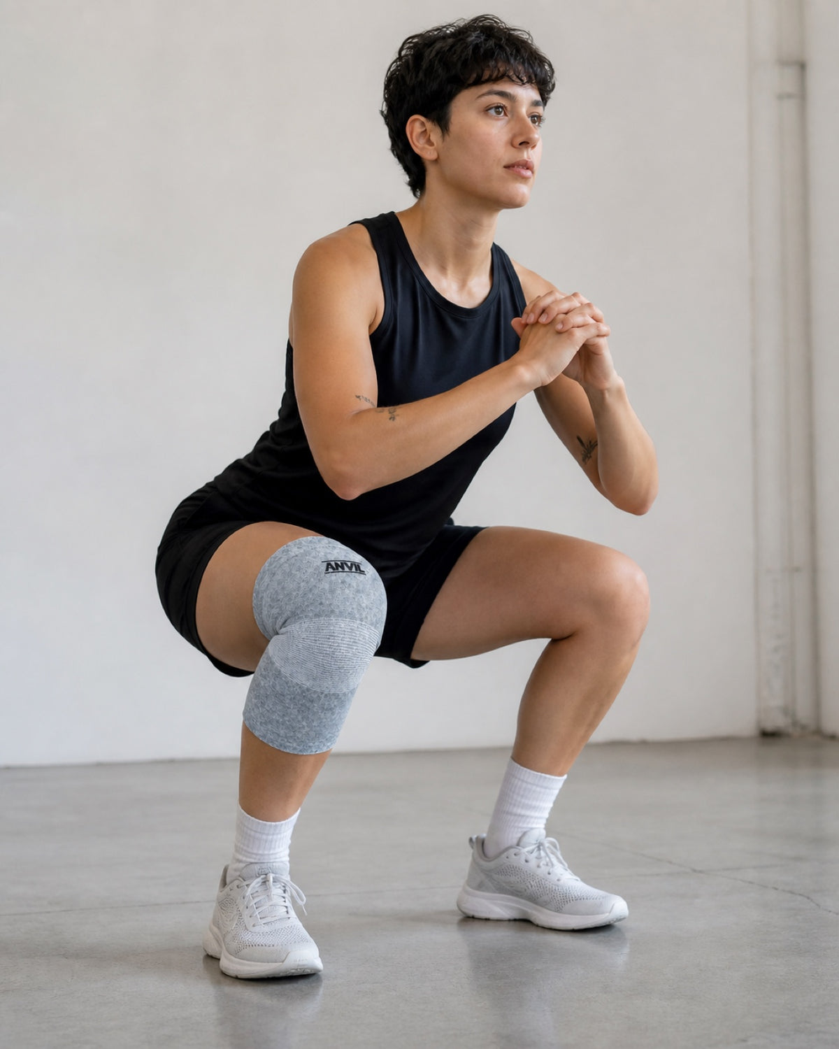 Athlete in a deep squat wearing a gray ANVIL knee sleeve.